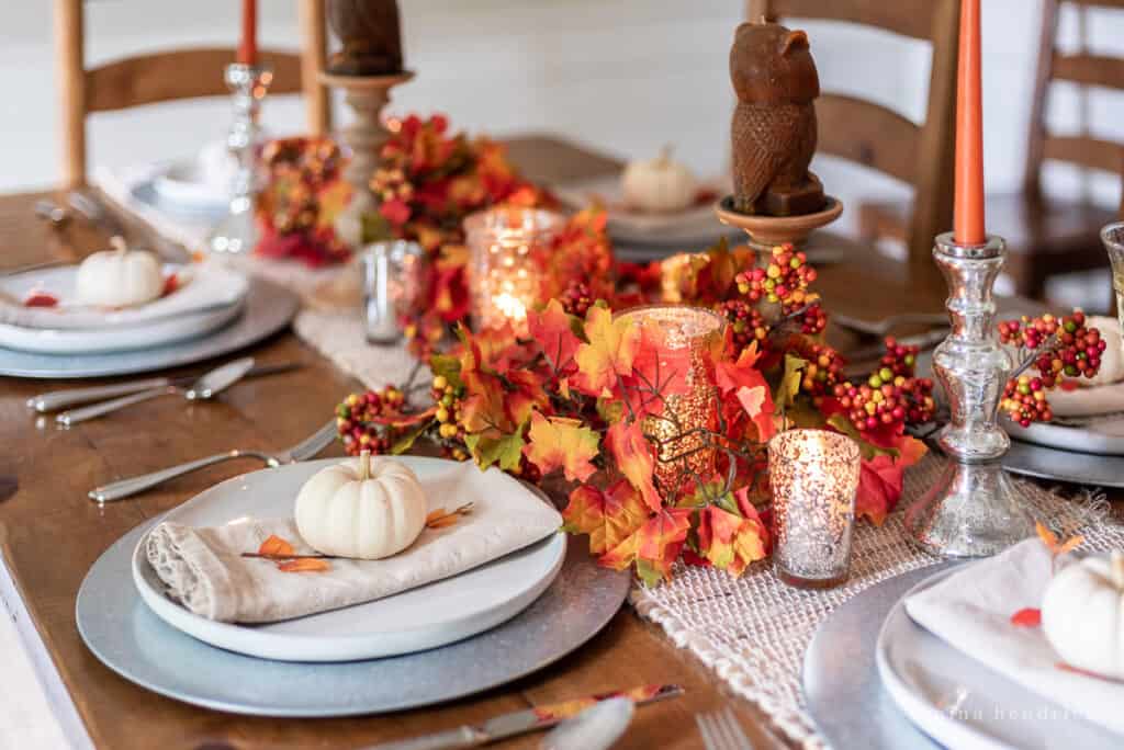 Festive fall table decor with candles and pumpkins.
