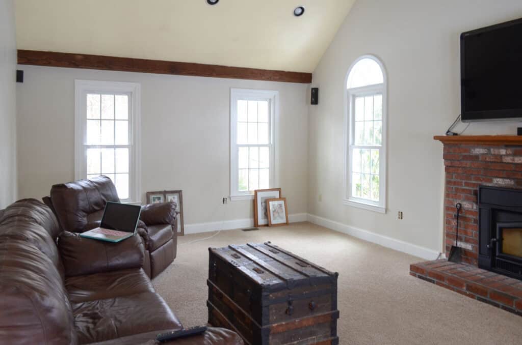 Family room before completing a renovation project with brown leather sofas and yellow ceilings.