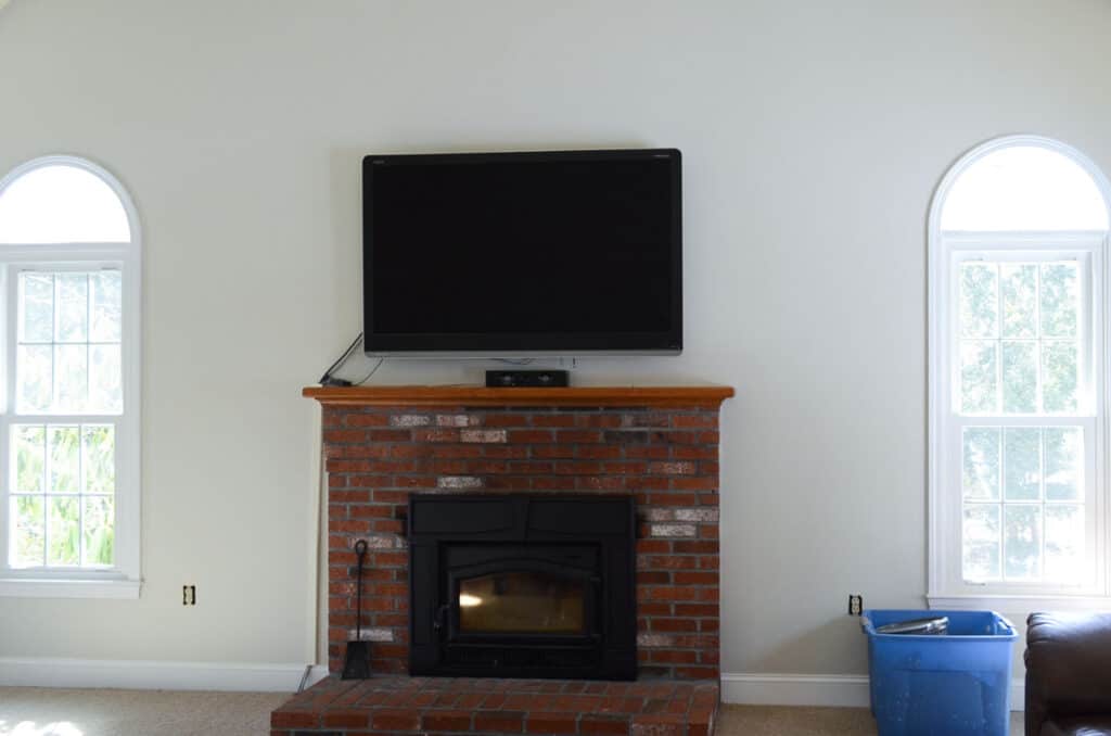 Family room painted Benjamin Moore Edgecomb Gray with brick fireplace and large TV