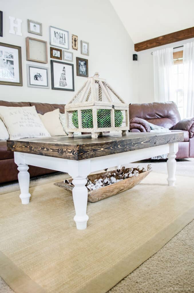 DIY wood cottage coffee table with a brown top and white legs in a living room with brown sofas.