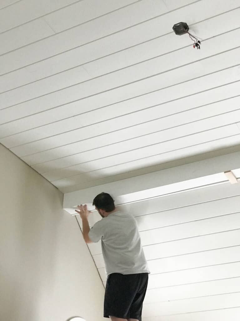 Covering a cathedral ceiling with white painted tongue-and-groove boards.