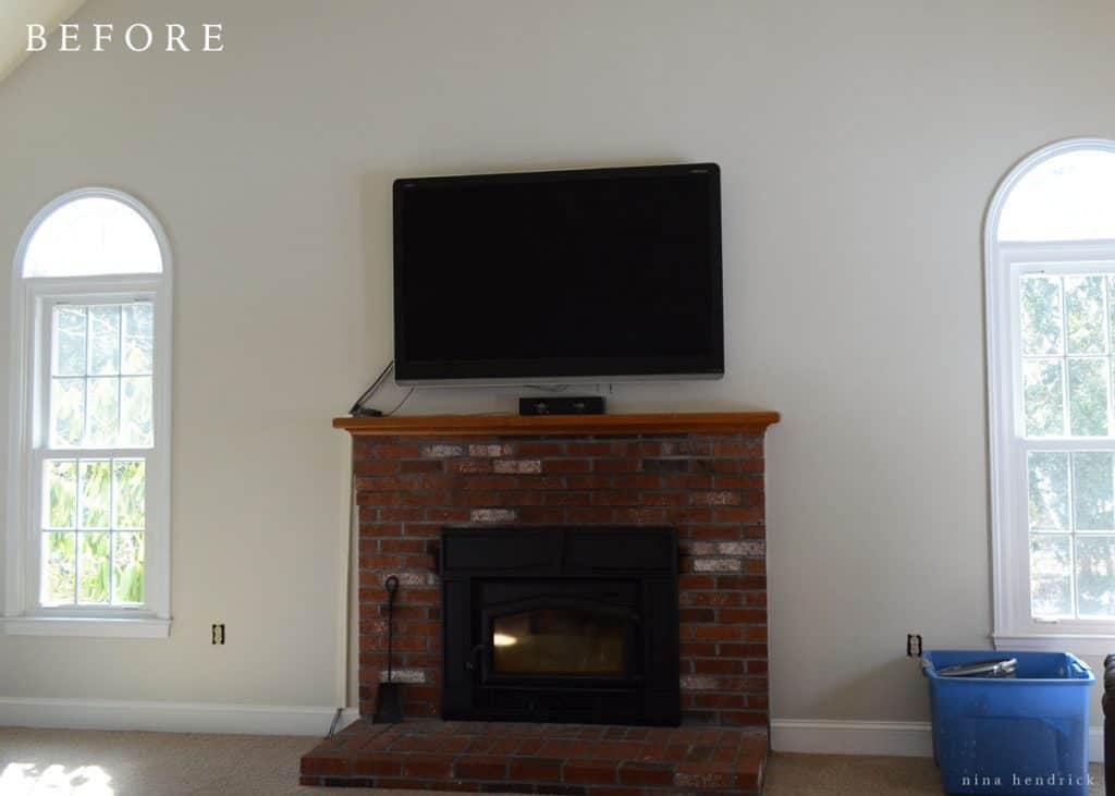 brick fireplace with wood mantel with a tv above it in a gray room