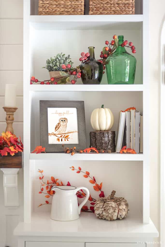 A white bookcase filled with fall decorations.
