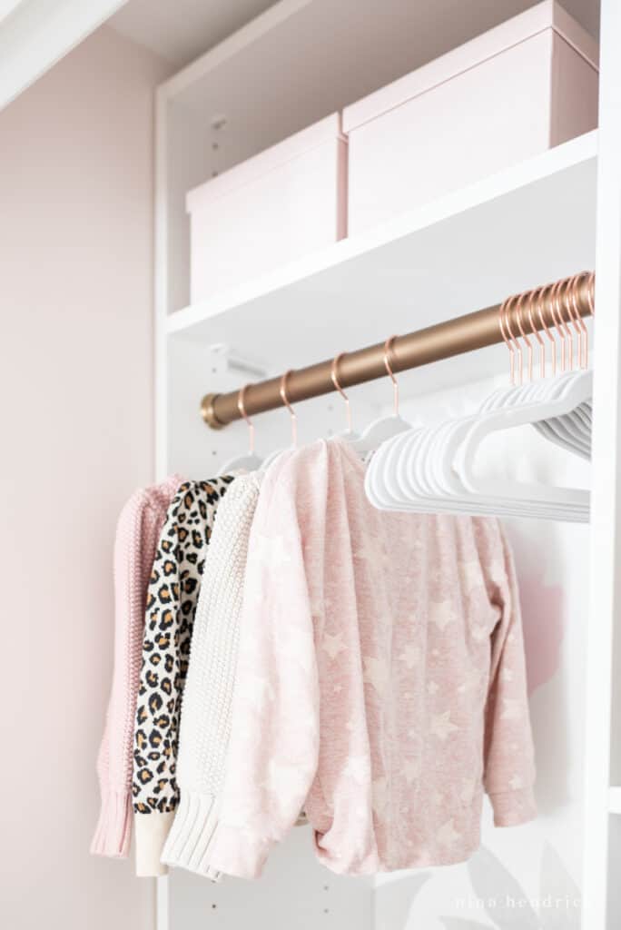 Girl's organized sweaters with gold closet rod and velvet hangers