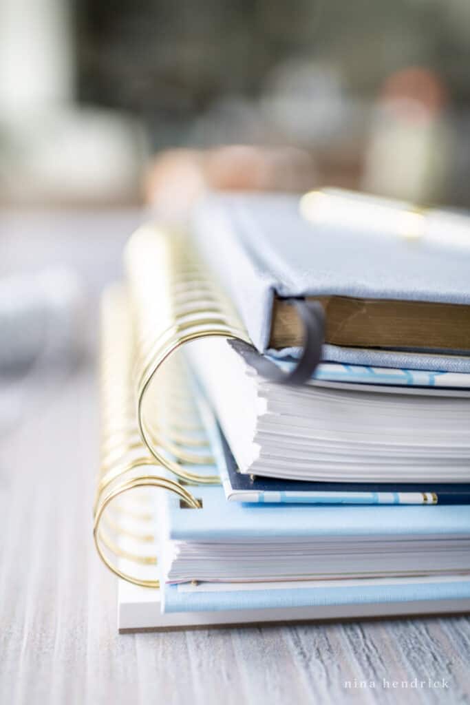 Stack of goal planning tools blue notebooks with gold coils