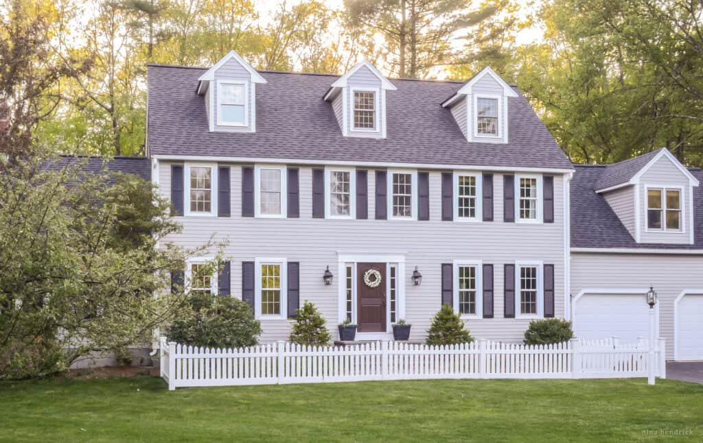 A home with gray siding and a white picket fence.