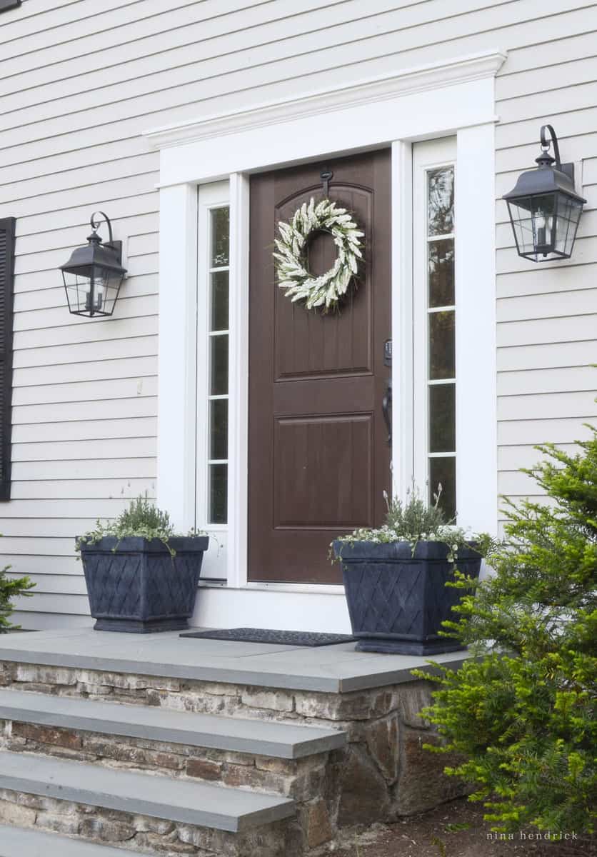 House with Gray Huskie paint, black planters, and a planked front door.