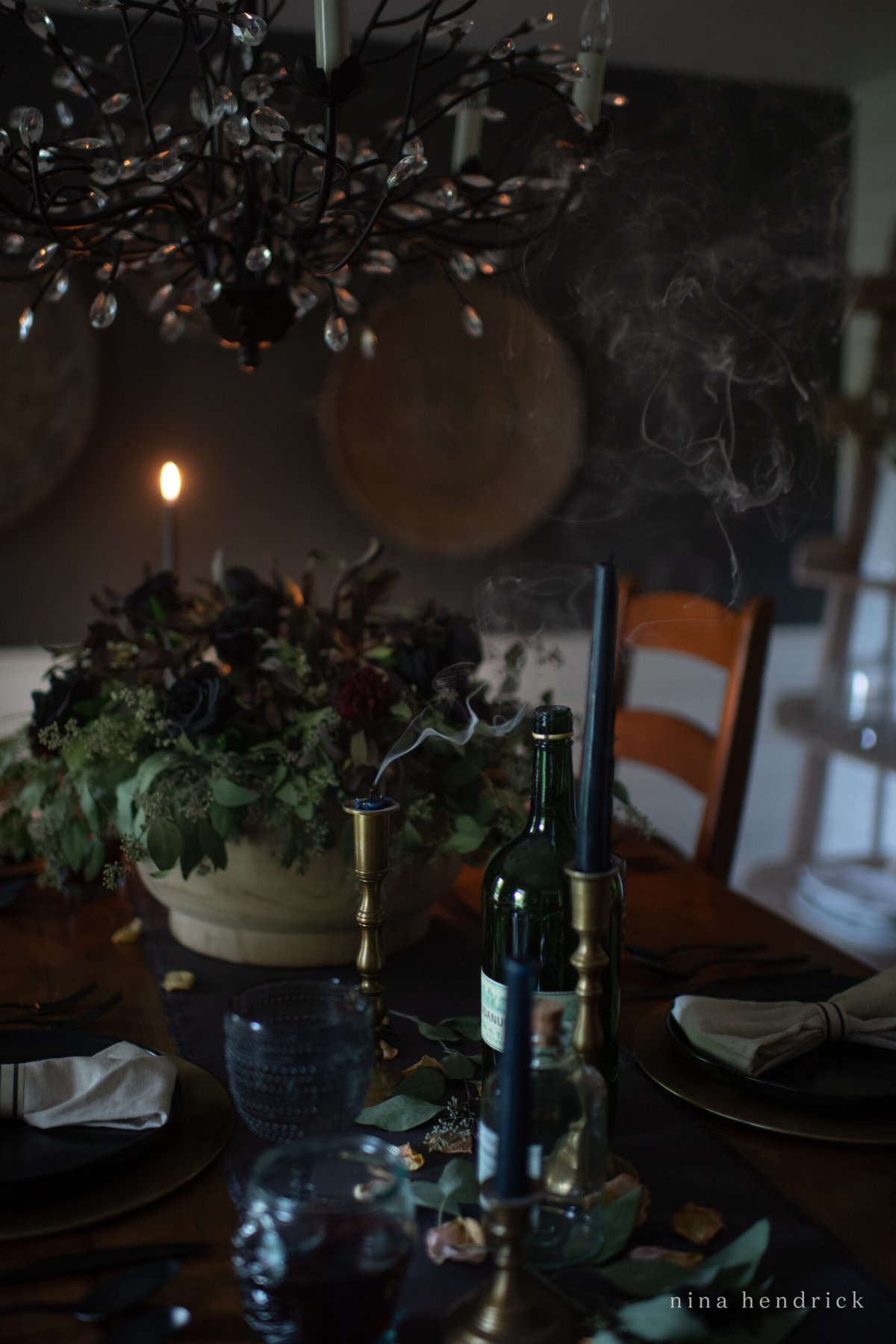 A dining room table is set with candles and wine glasses, perfect for an elegant Halloween party.