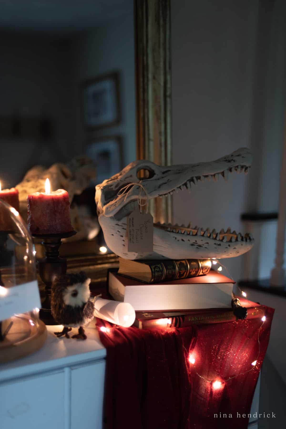 Get spooky this Halloween with a table adorned with books, candles, and a crocodile skull. Perfect for your haunted house or Halloween party, this eerie centerpiece is sure to impress guests and set