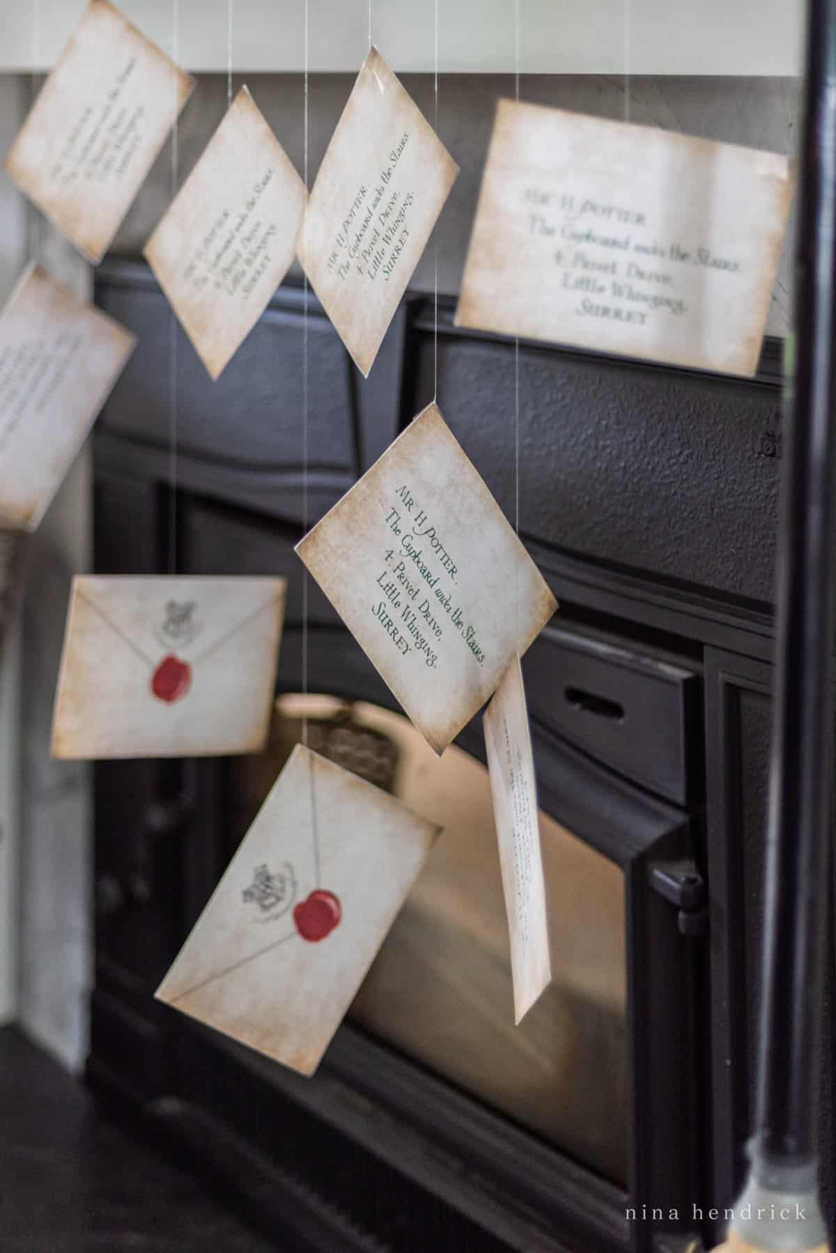 Harry Potter invitations in the form of Hogwarts acceptance letters, elegantly hanging from a fireplace.