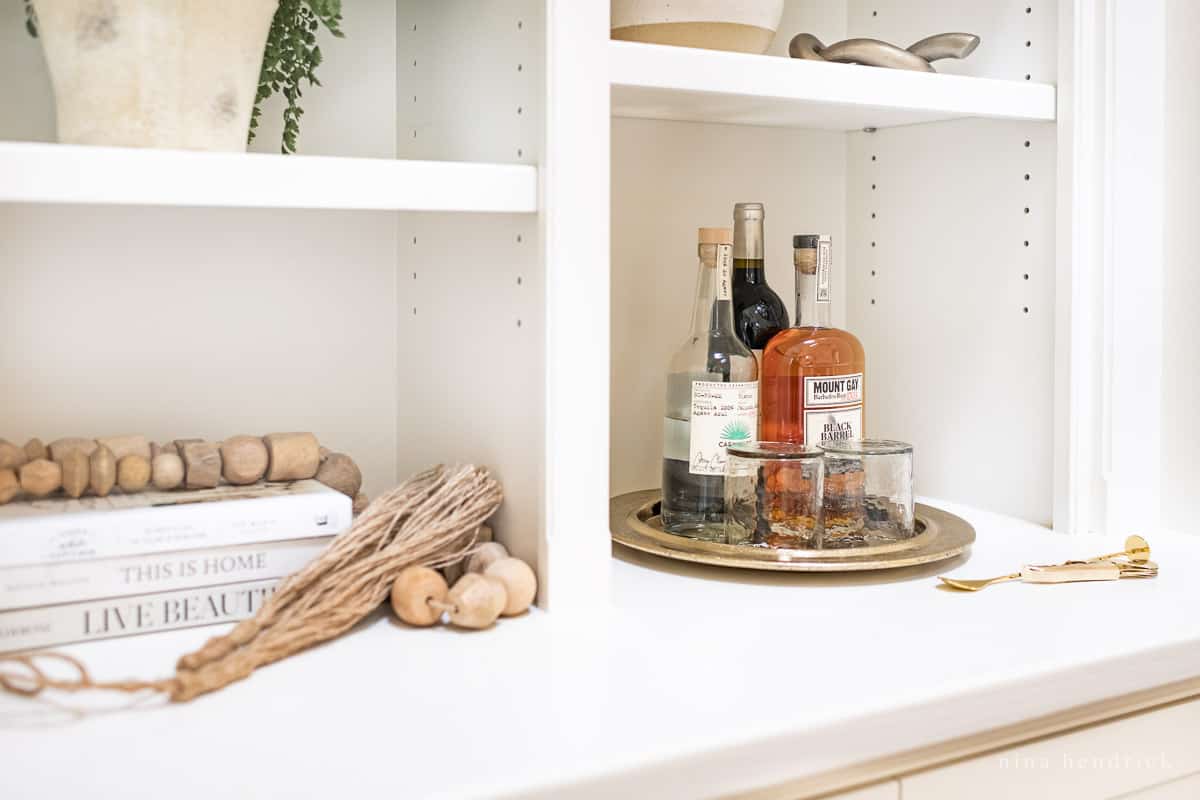 Built-in shelves with liquor on brass tray
