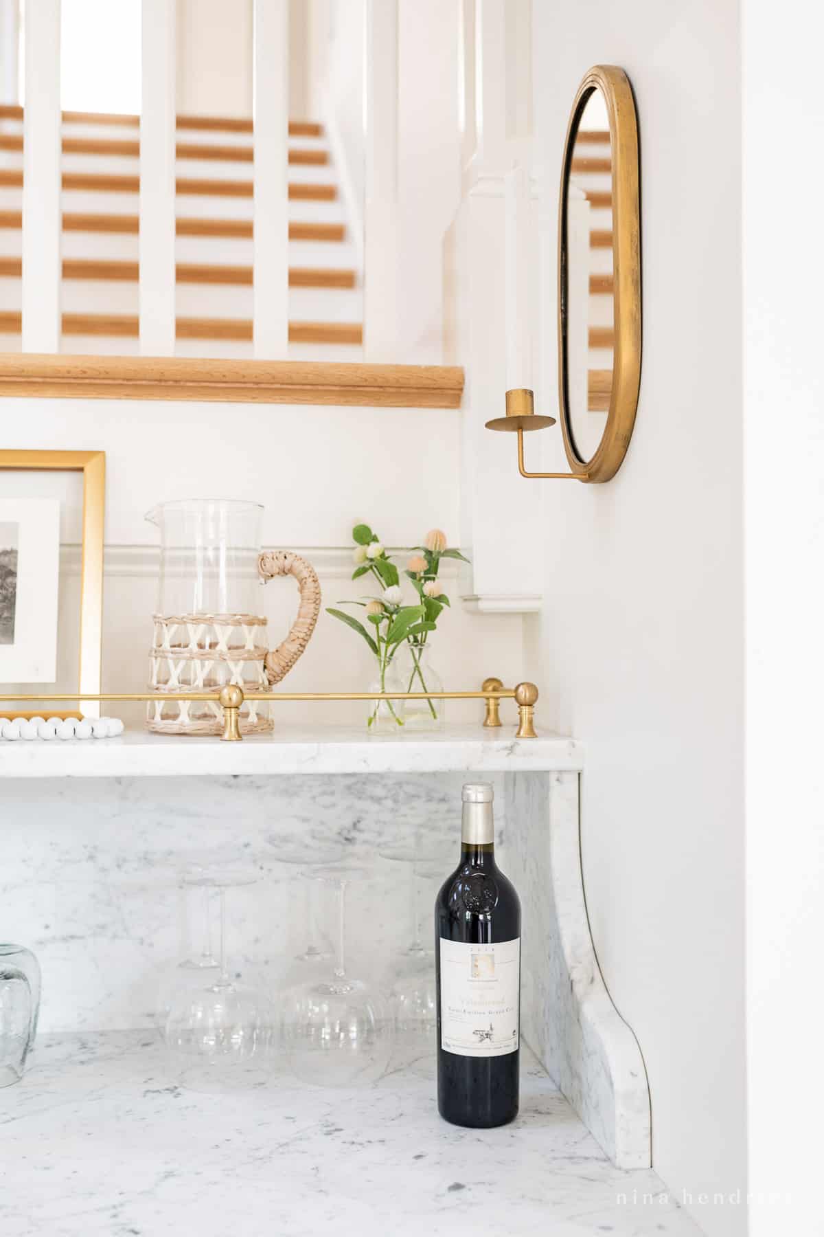 Wine glasses and bottle with brass sconce and marble built-in