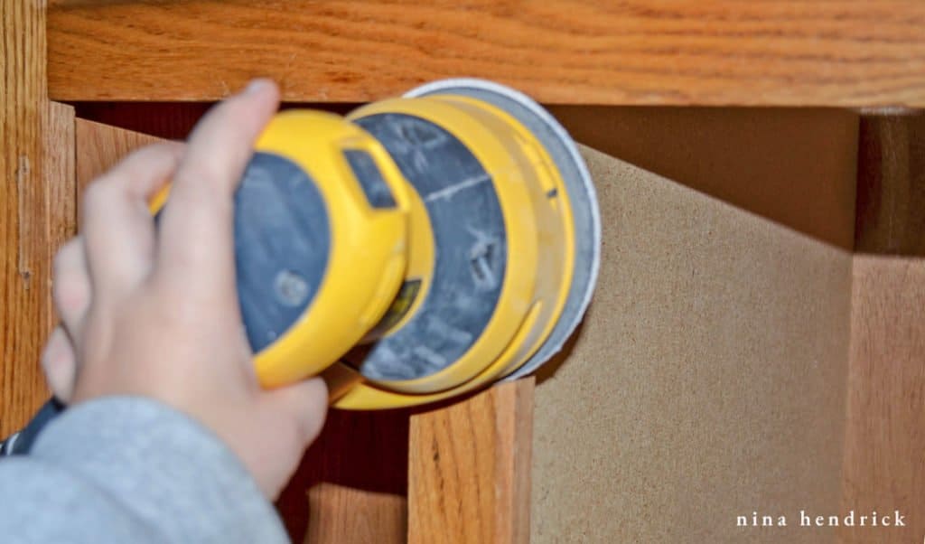 How to Paint Oak Cabinets Tutorial: Sand the cabinet faces with 80 grit sandpaper.