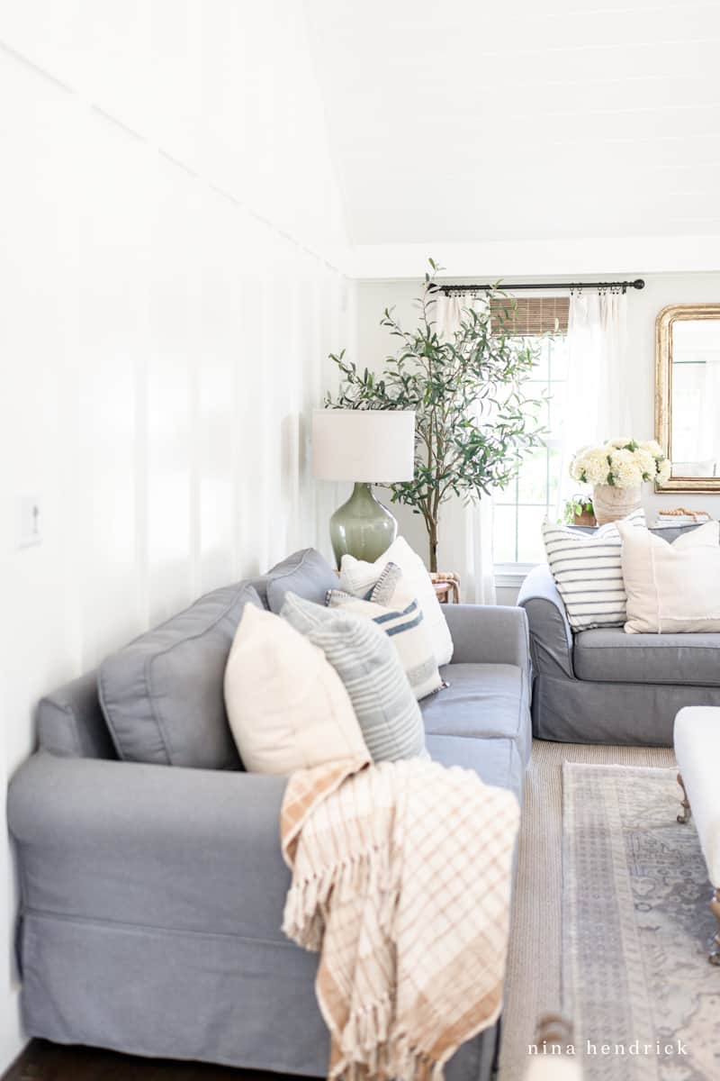 Blue gray sofa up against a white board-and-batten wall