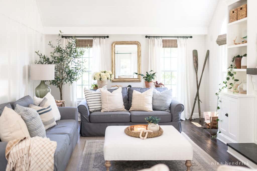 Family room decorated with natural and neutral style with white walls and a charcoal sofa.