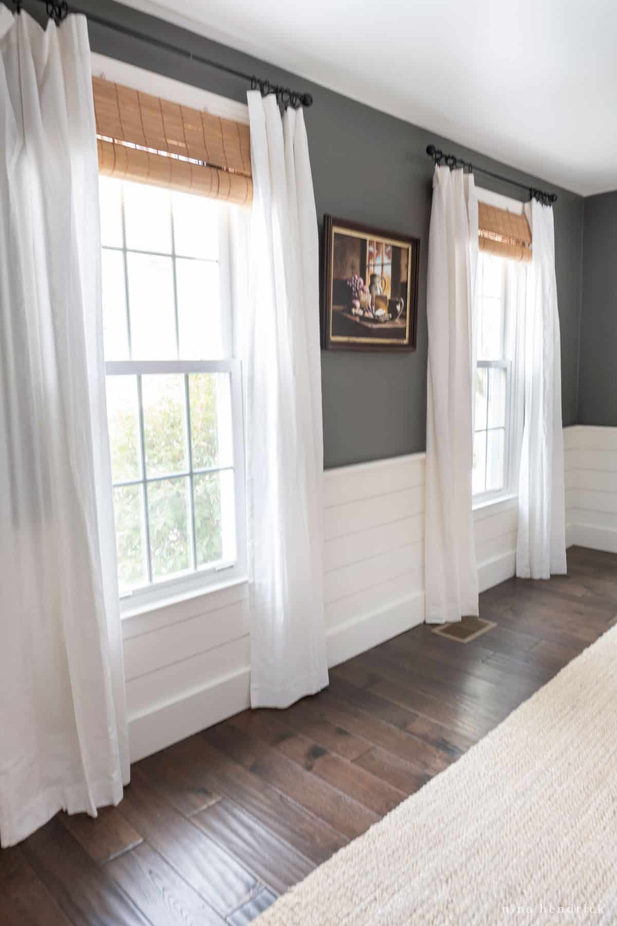 Dining room with charcoal walls, shiplap, inexpensive window treatments of sheer curtains with wooden blinds, and hardwood floors