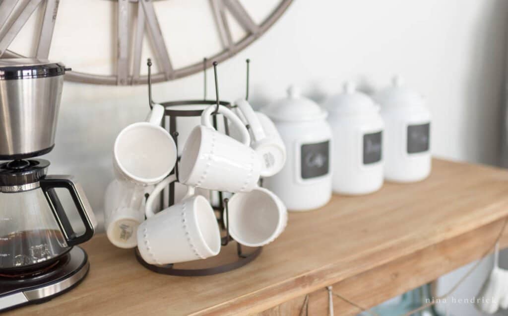 mugs on a mug tree and white jars