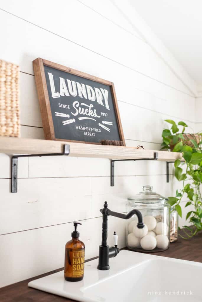 laundry sucks sign over a white farmhouse sink