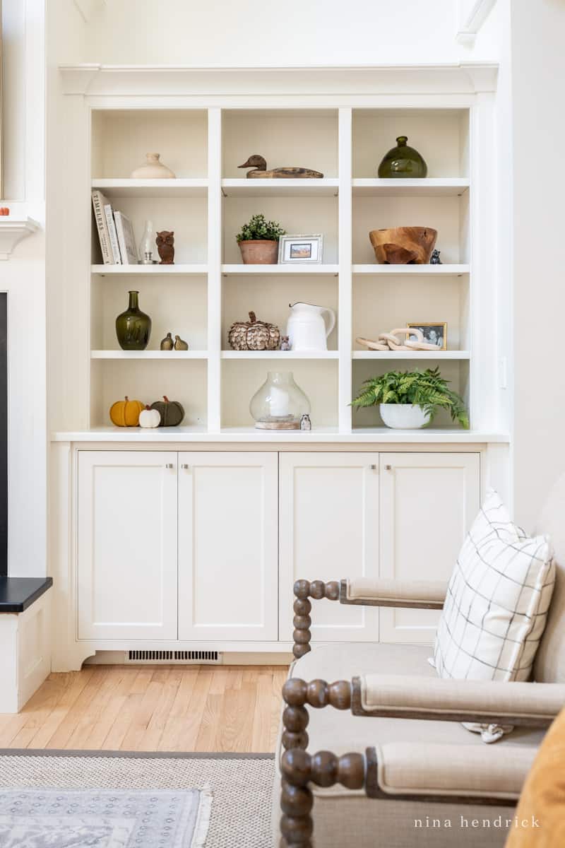 A living room with white bookshelves and a fireplace.