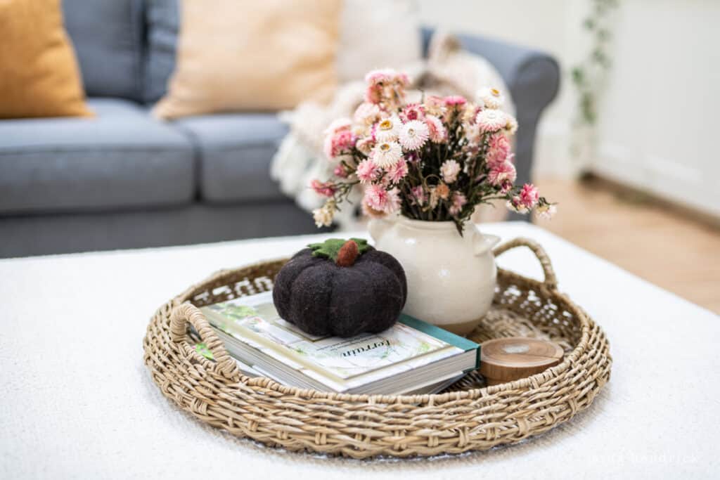 A wicker tray with flowers and books on it.