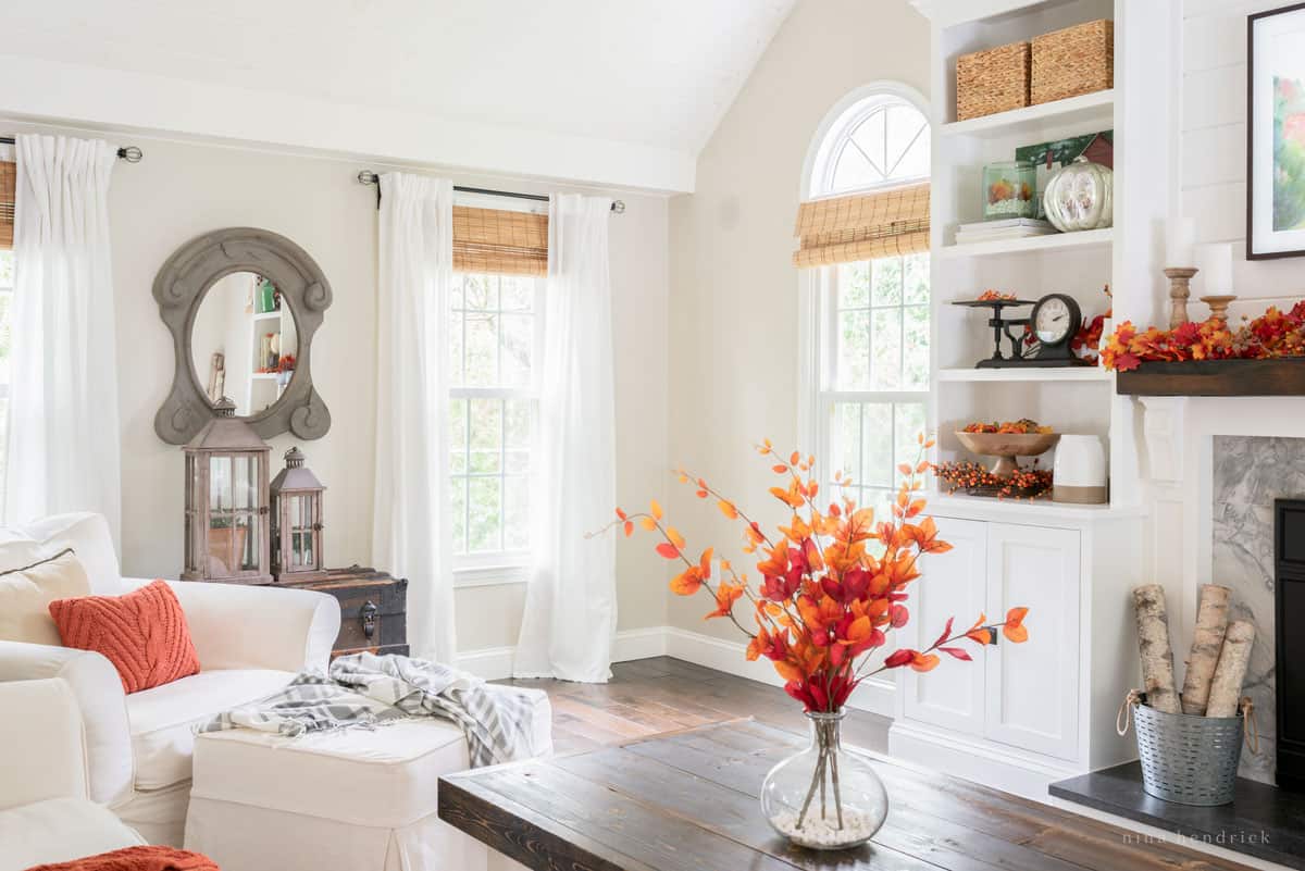 A living room with a fireplace and fall decorations.