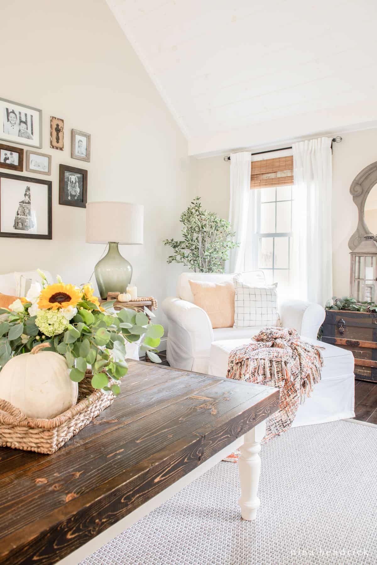 A living room with a wooden table and a vase of sunflowers.