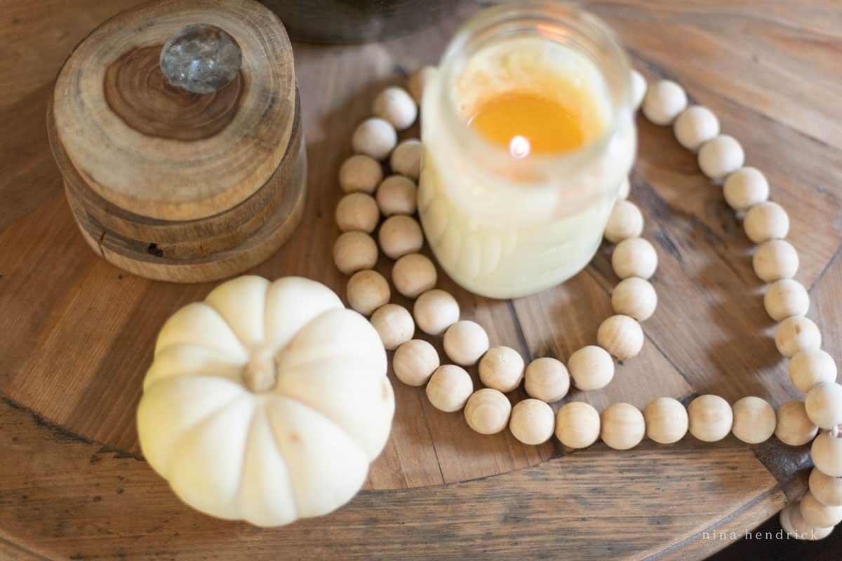 A candle and wooden beads on a wooden table.