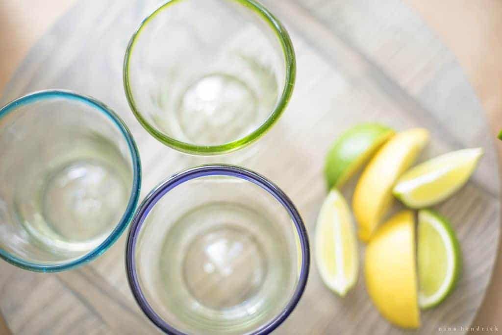 Overhead shot of colorful lowball glasses with lemon and lime wedges