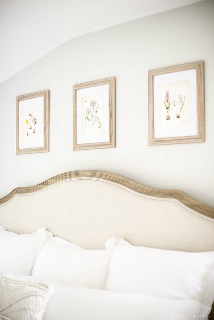 Series of three framed prints above a bed with botanical artwork.