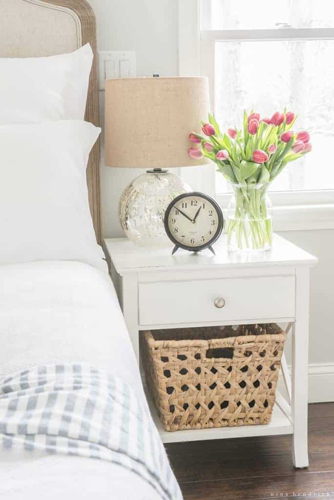 White nightstand with fresh flowers and a mercury glass lamp