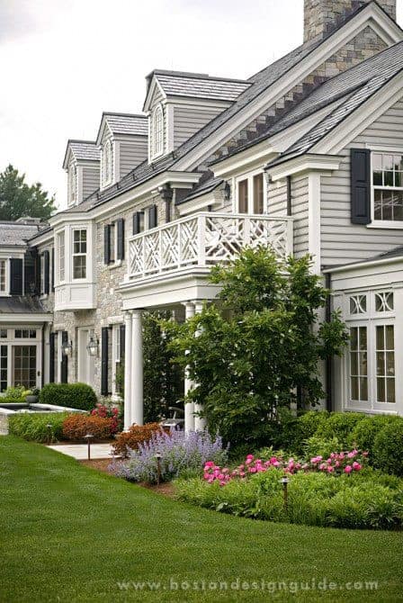 A traditional New England-style home with a large front porch and landscaping.