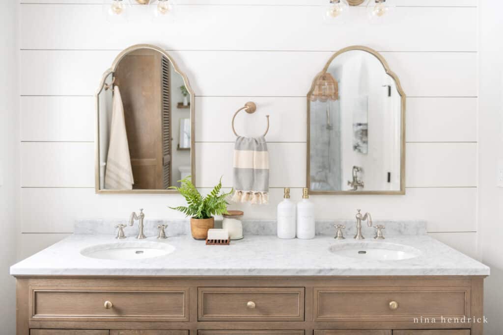 Mixing metals in a bathroom brushed brass mirrors and nickel faucets. 