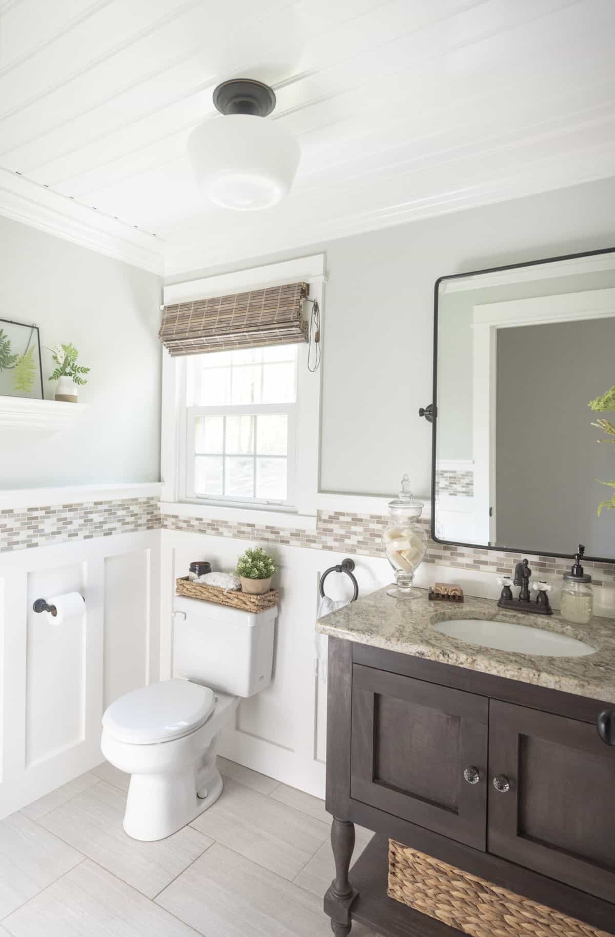 Powder bathroom with gray tile floor and a wall treatment with mixed tile border