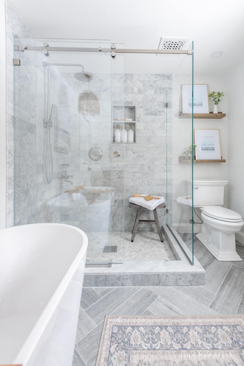 gray tile bathroom with herringbone floor pattern mixed with Carrara marble 
