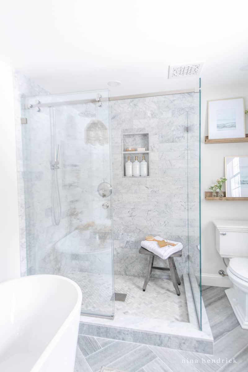 Mixing tile in a primary bathroom: gray cement-look, marble subway, and herringbone mosaic
