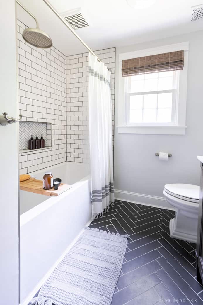 Bathroom with dark gray herringbone floor mixed with white subway tiles in the shower