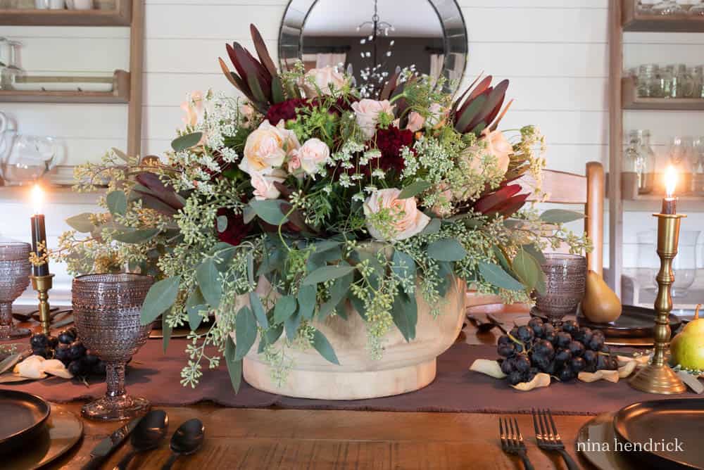 Large floral arrangement in a wooden bowl with fall colors