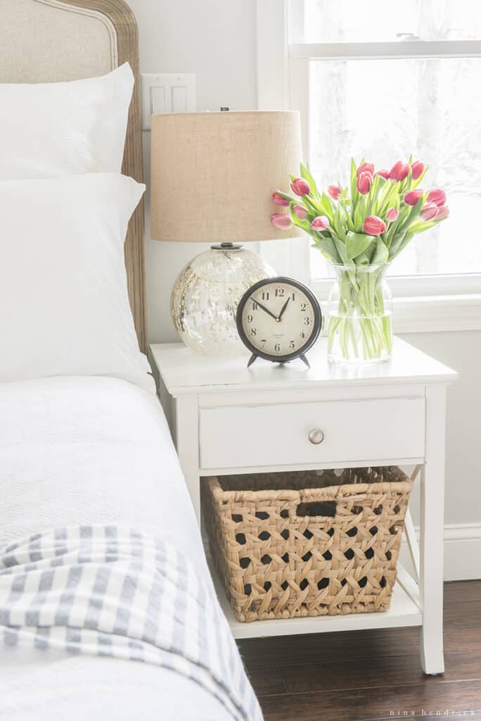 Practing a morning routine by getting up early, alarm clock on nightstand with flowers