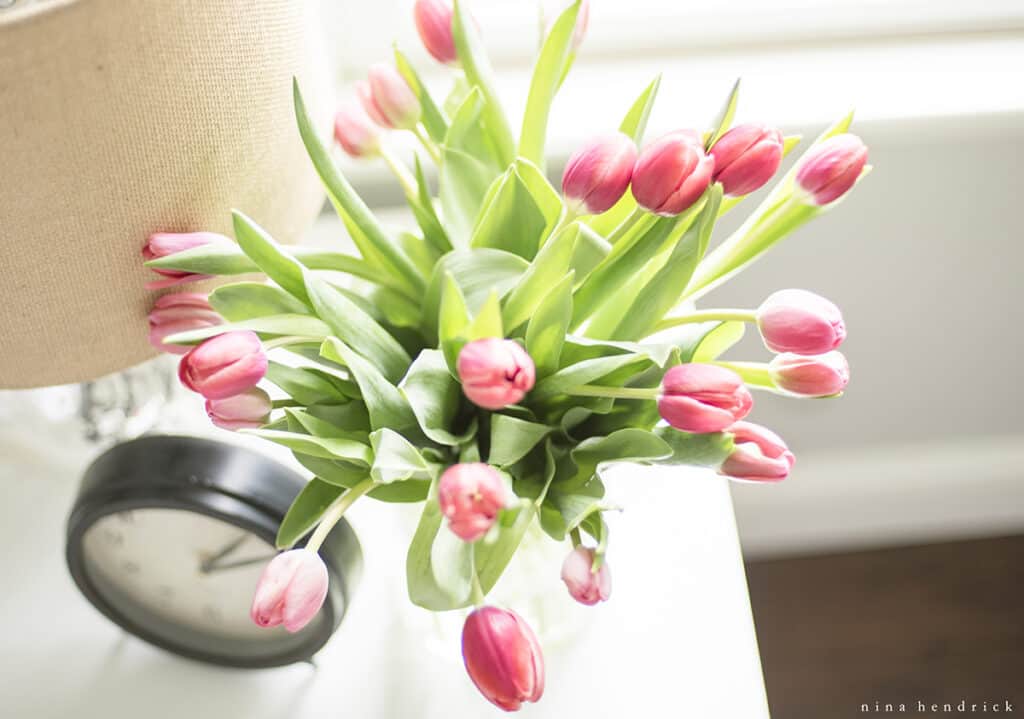 Flowers and a clock on nightstand