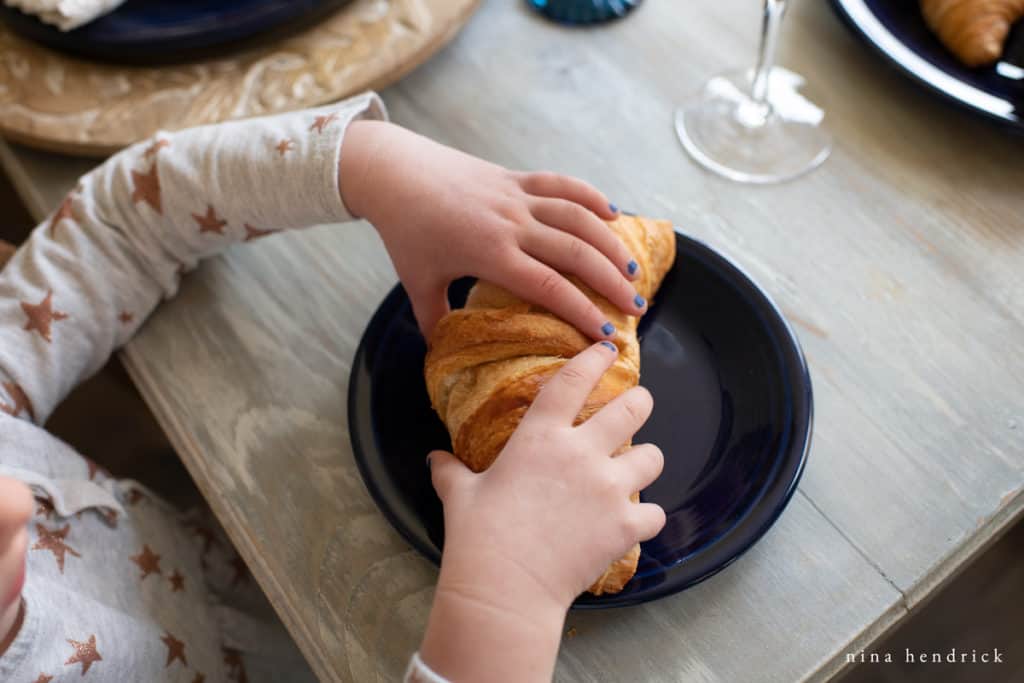Little girl reaching for Croissant