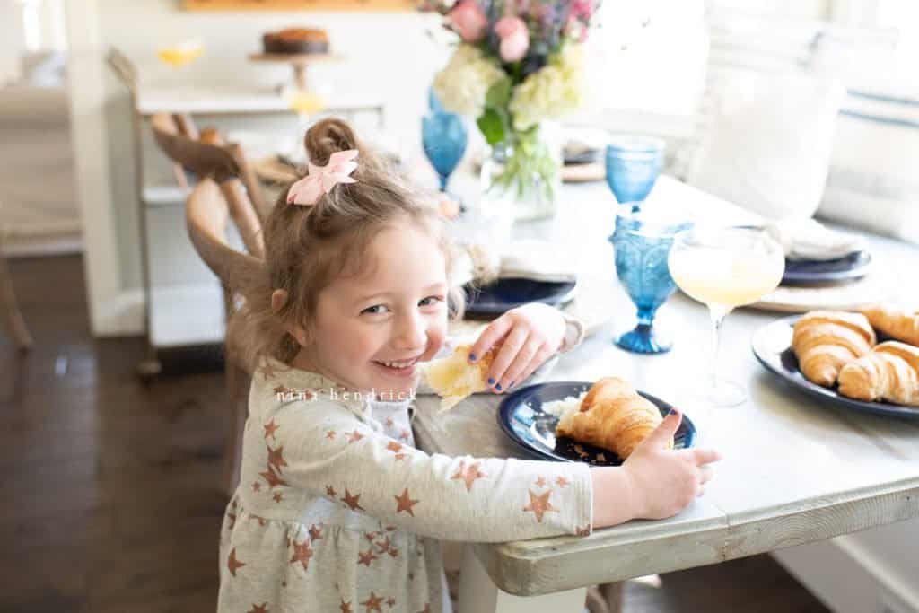 Little girl eating a croissant at Mother's Day Brunch.
