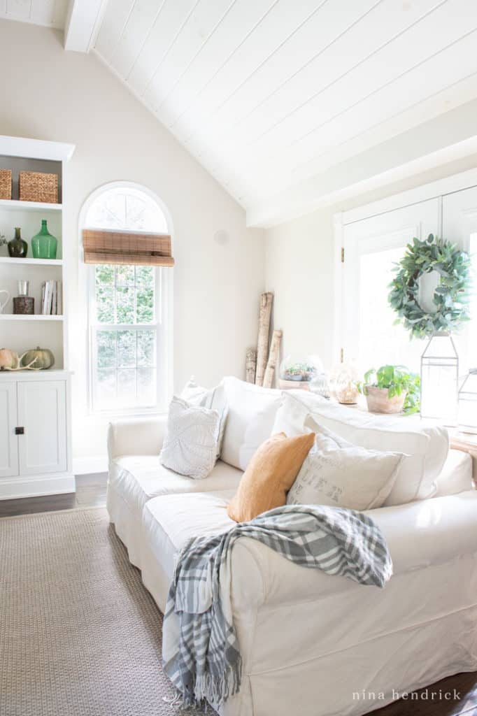 white sofa with muted fall pillows and heirloom pumpkins in the family room