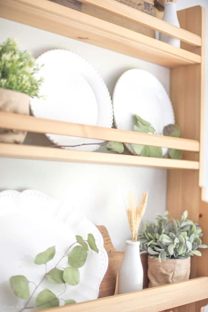 Wooden shelf with white plates and natural elements