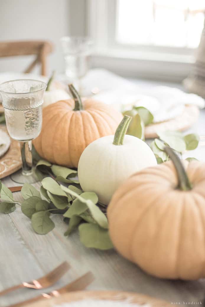 Simple fall tablescape featuring pumpkins and eucalyptus leaves.