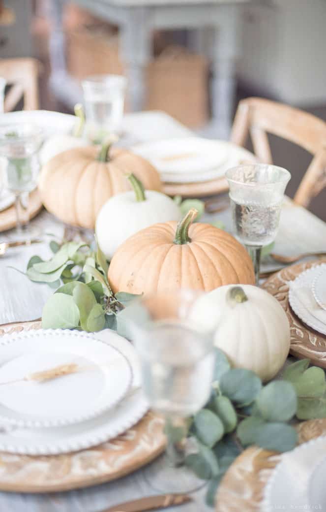 Simple Thanksgiving table setting with pumpkins and eucalyptus in a fall tablescape.