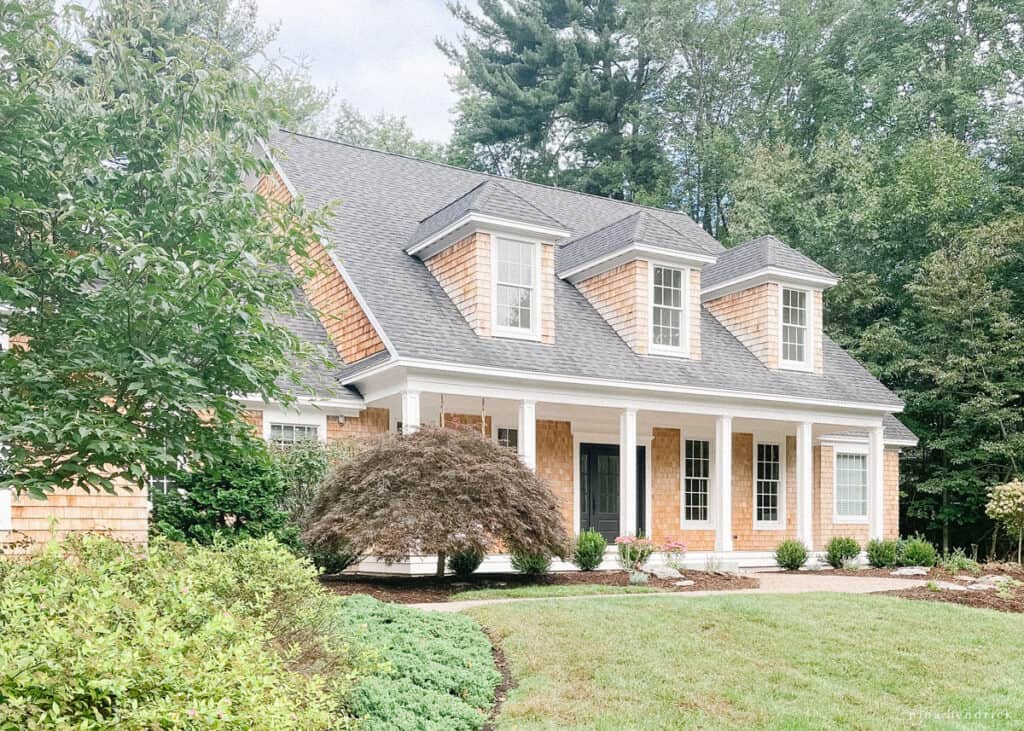 A Coastal Cape Cod New England style home with a large front porch and yard.