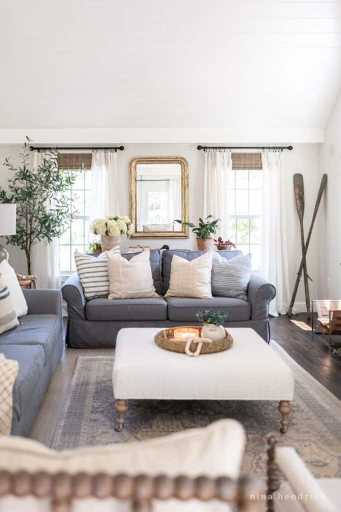 Gray Slipcovered sofas with neutral pillows and oar decor