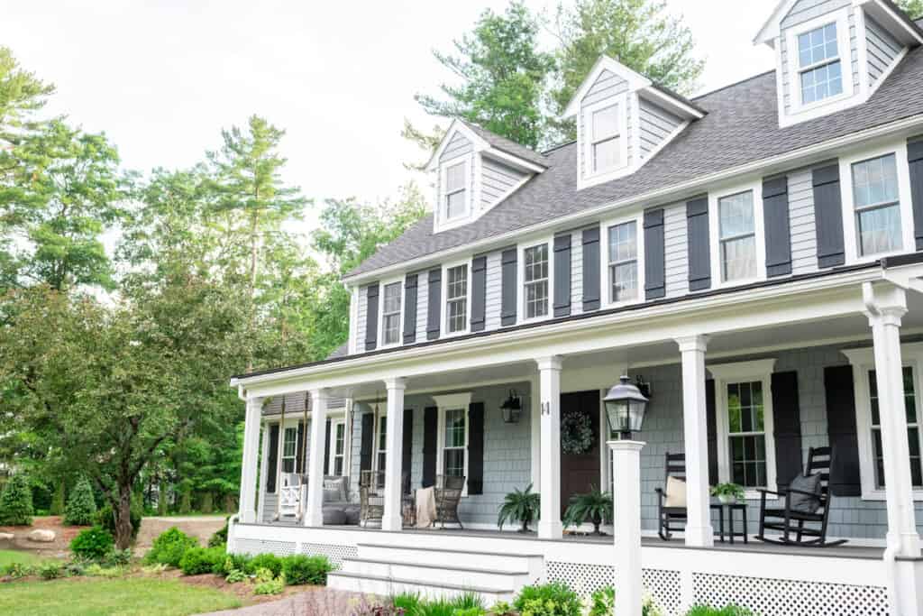 New England Colonial with three dormers and black shutters with farmer's porch