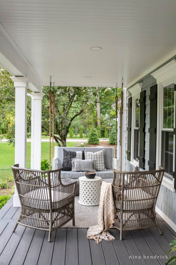 Farmer's porch with gray wicker chairs and bed swing to make up a relaxing conversation area