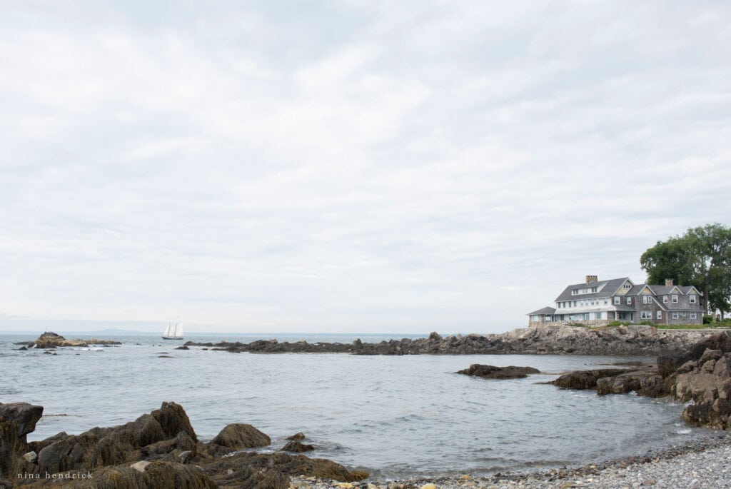 A rocky shore with a New England style home.